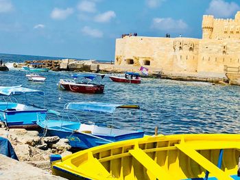 Boats moored on sea against buildings