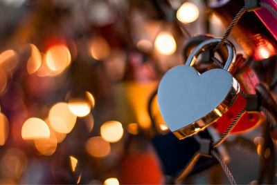 Close-up of illuminated string lights and a heart shaped lock