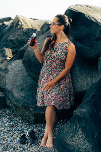 Attractive woman in a dress on the beach with a refreshing drink in a glass bottle with a straw. 