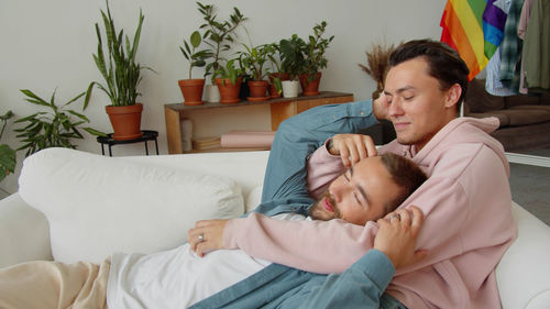 Young woman using mobile phone while lying on bed at home