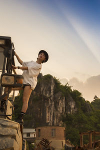 Man standing by building against sky