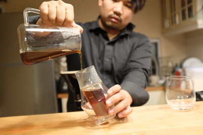 Midsection of man pouring wine in glass on table