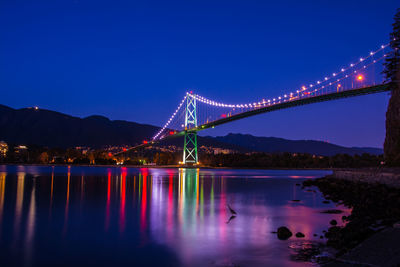 Illuminated suspension bridge over river at night