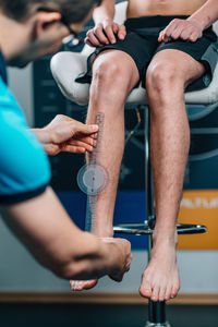 Man measuring male athlete leg in health club