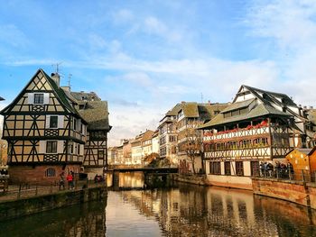 Bridge over river by buildings in city against sky