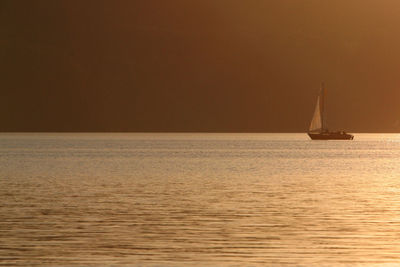 Sailboat sailing on sea against sky during sunset