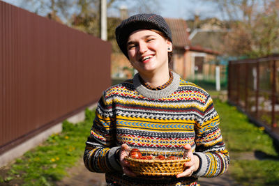 Happy smiling woman holding basket of colored red eggs, easter holiday concept. hands holding modern