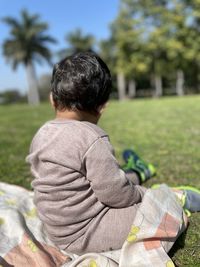 Rear view of boy sitting on field