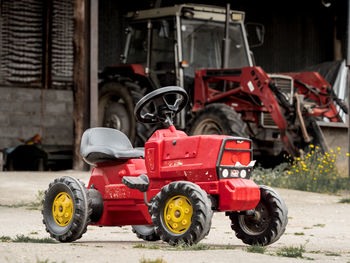 A toy tractor with a real tractor in the background 