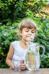 Portrait of young woman drinking water from bottle on table