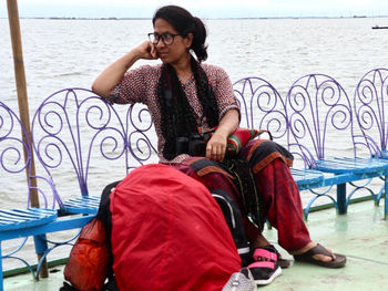 Woman sitting on railing by river