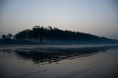 Scenic view of beach against clear sky at sunset