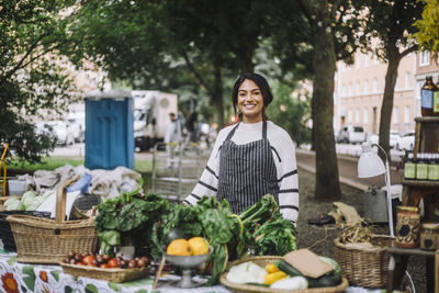 Portrait of smiling female vendor selling vegetables at farmer's market