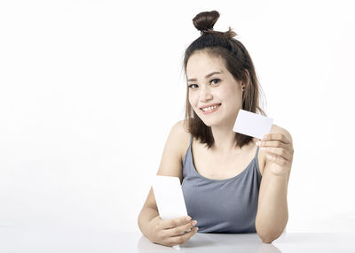 Portrait of smiling young woman using smart phone against white background