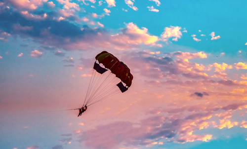 Low angle view of silhouette people parasailing against sky during sunset