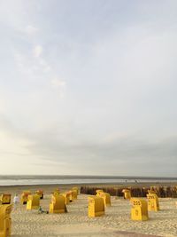 Hooded chairs on beach against sky