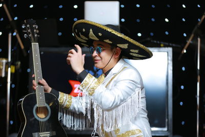 Young man wearing sunglasses and hat holding guitar