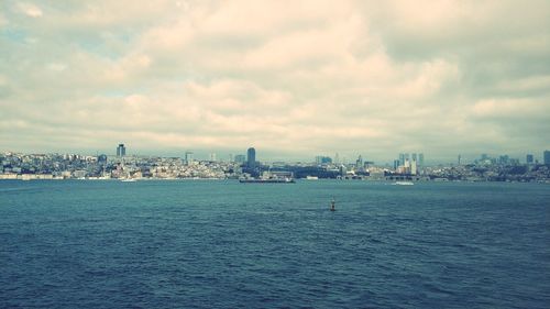 Sea by buildings against sky in city