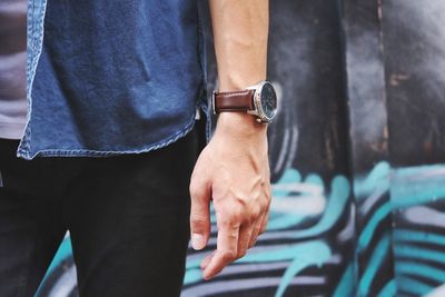 Midsection of man standing against wall