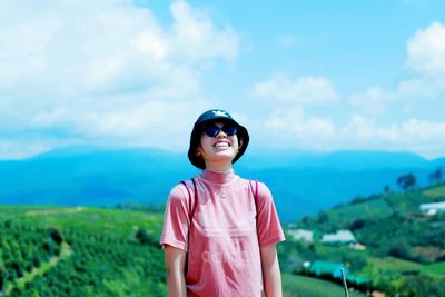 Portrait of smiling man standing on field against sky