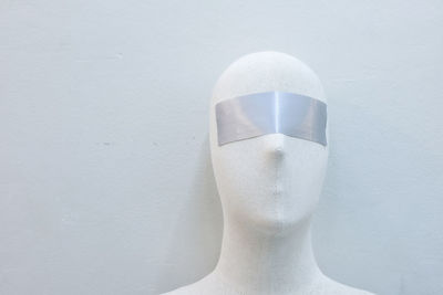 Close-up of mannequin with blind fold against wall