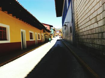 Empty road amidst buildings against sky