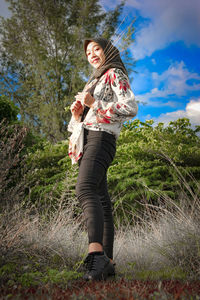 Full length of woman standing on field against sky