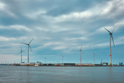 Wind turbines in antwerp port on sunset.