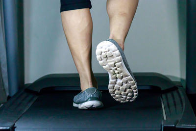 Low section of man exercising on treadmill in gym