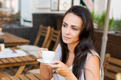 Positive business woman sitting in outdoor cafe drinking coffee.