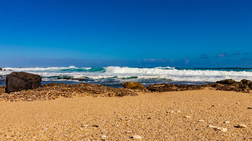 Scenic view of beach against blue sky