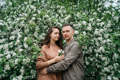 Young couple in love girl and man hugging blooming apple tree aroma of flowers outdoors