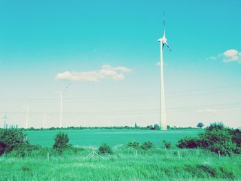 Windmill on field against blue sky
