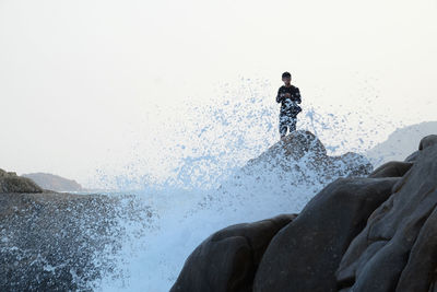 Man standing at beach against clear sky