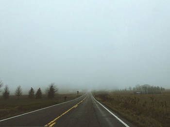 Road by trees against sky