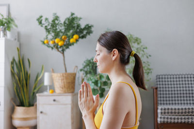 Side view of young woman using mobile phone at home