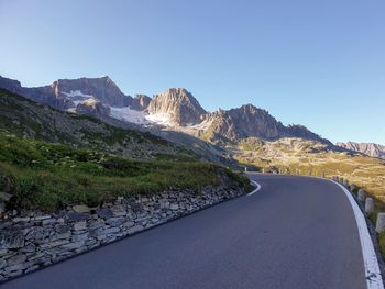 Road leading towards mountains against clear sky