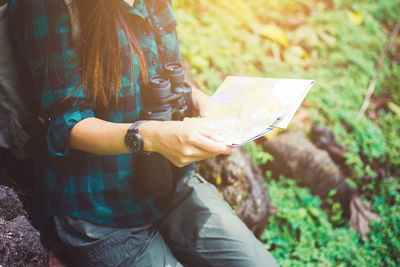 Midsection of woman holding umbrella against trees
