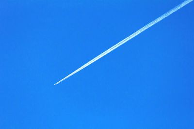 Low angle view of vapor trail against clear blue sky