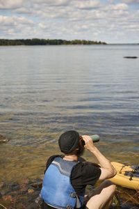 Man sitting at lake and drinking from water bottle