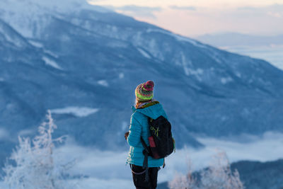 Woman in warm clothing standing on mountain during winter