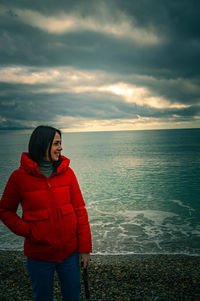 Portrait of young woman standing against sea
