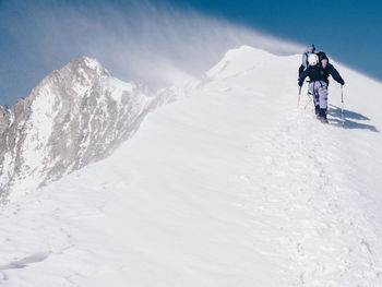 Man skiing on snow covered mountain against sky