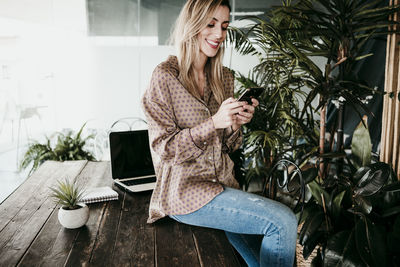 Young woman using mobile phone while sitting on table