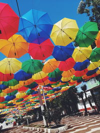 Low angle view of multi colored umbrellas hanging against sky