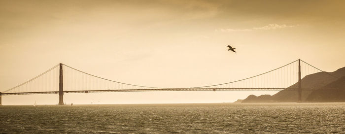 View of suspension bridge over sea against sky