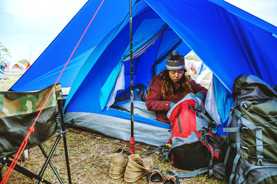 Young woman with backpack sitting in tent