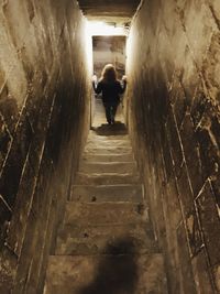 Rear view of woman walking in tunnel