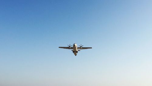 Low angle view of airplane flying against clear blue sky