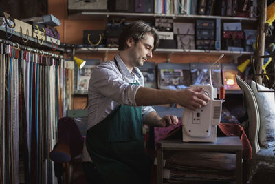 Male tailor using sewing machine in design studio